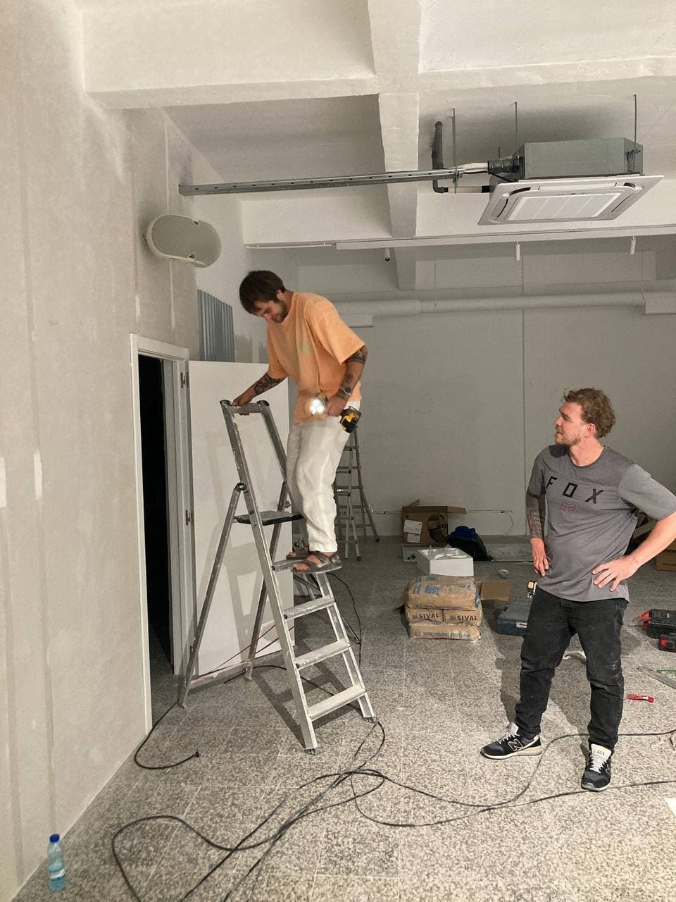 Installation team working on ceiling-mounted equipment inside the venue