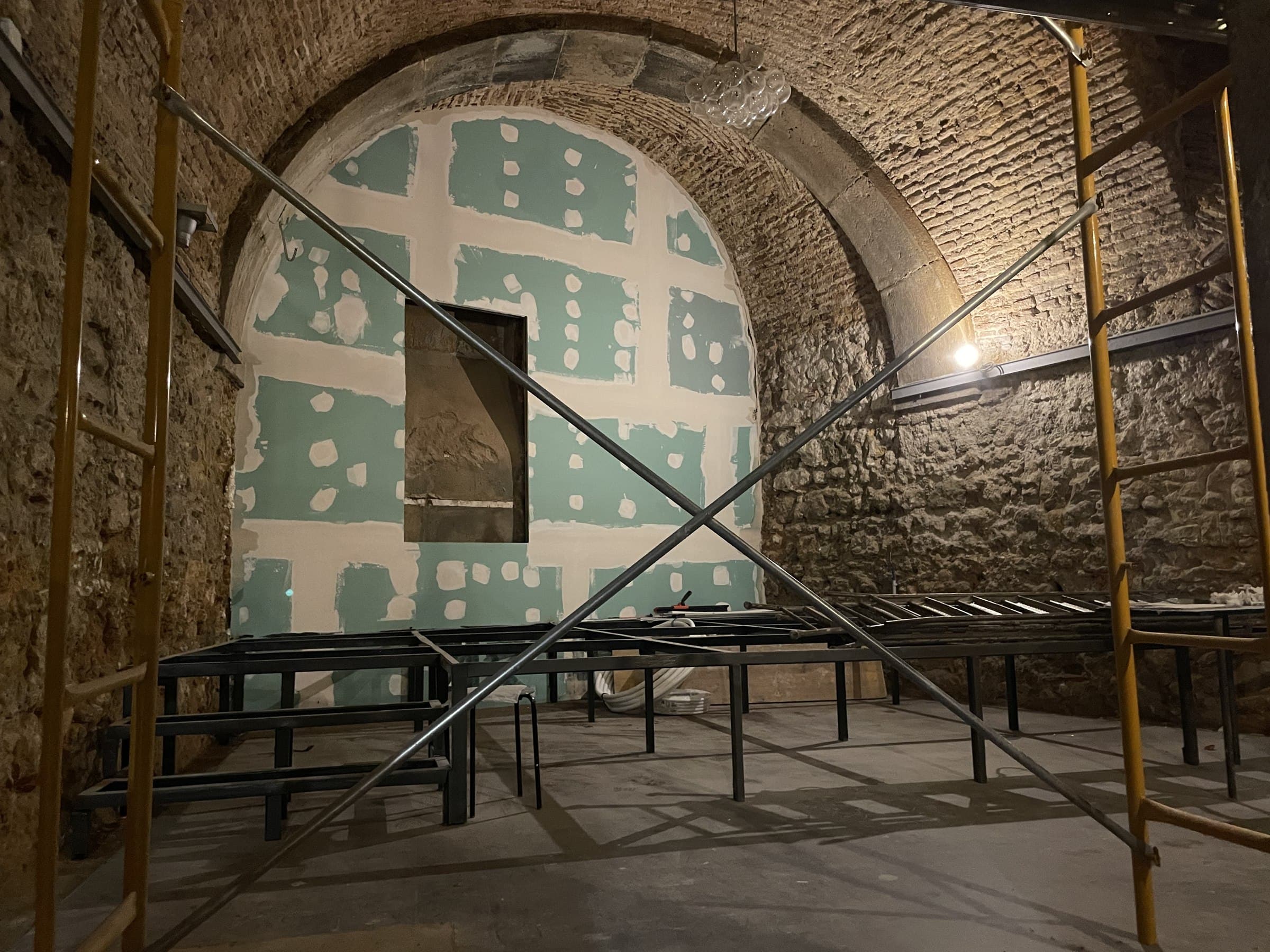 Vaulted stone cellar during construction, with ductwork and a mezzanine under way