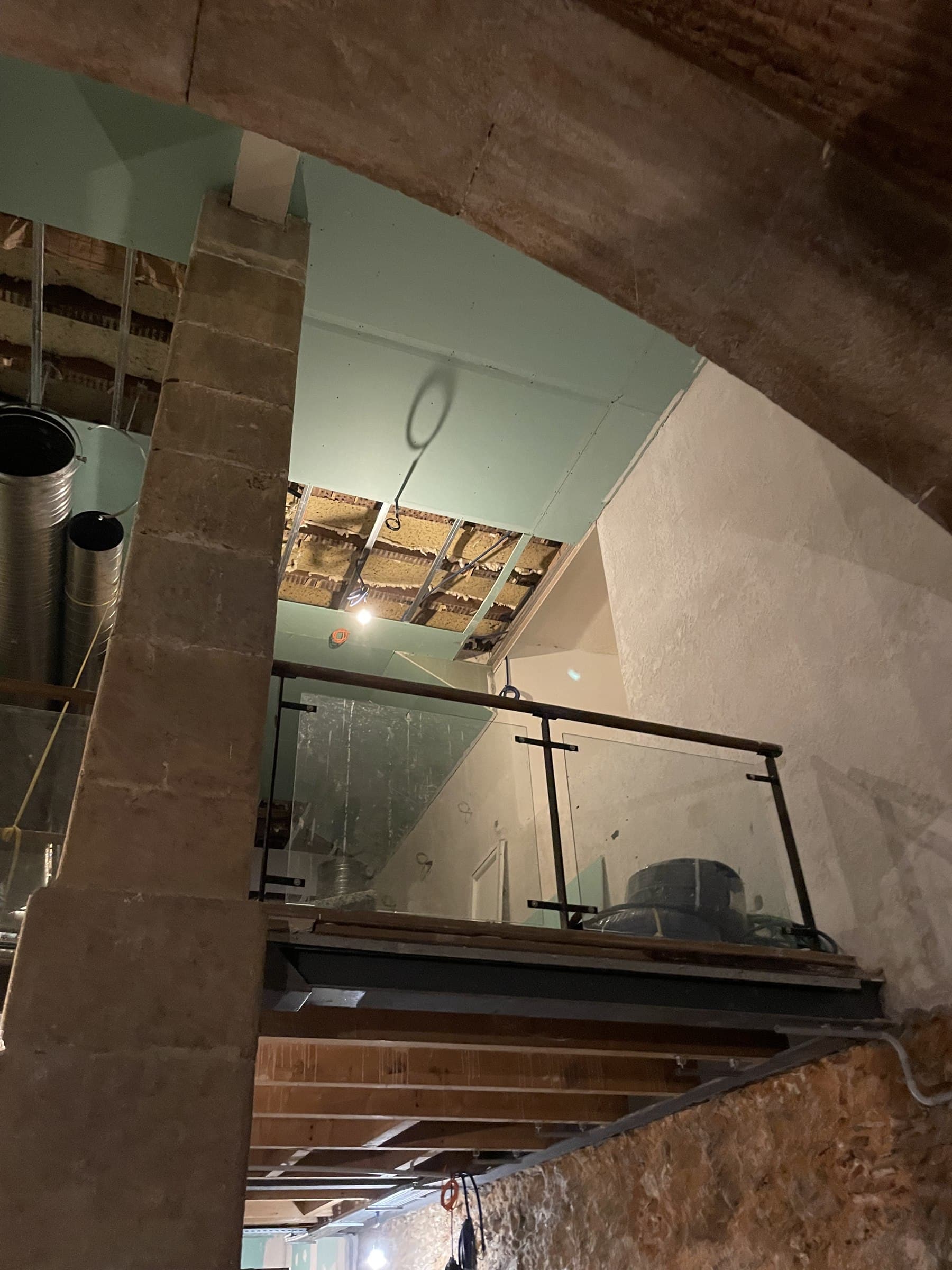 Glass balustrade mezzanine overlooking the stone-vaulted lower floor